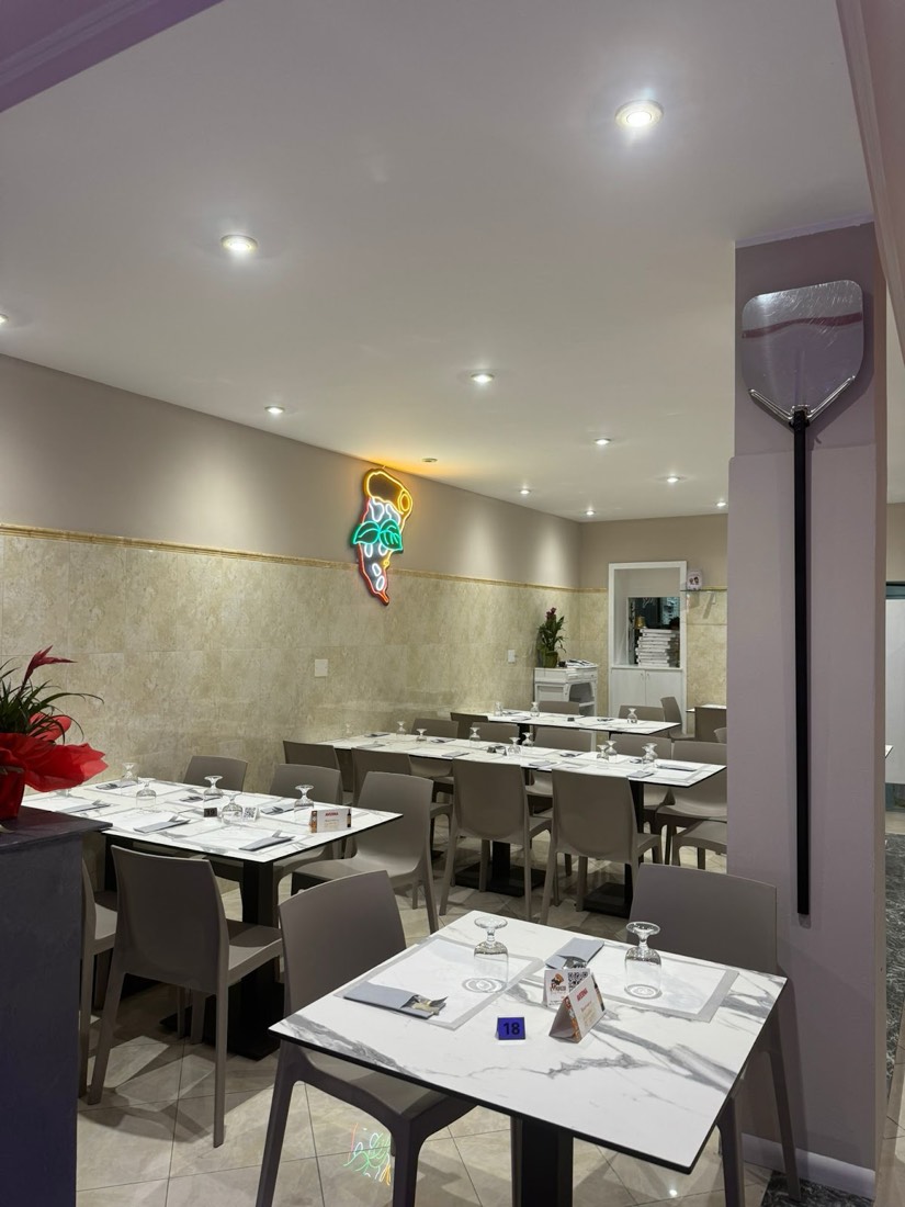 La sala della pizzeria Papiedo con l'insegna al neon a forma di spicchio di pizza